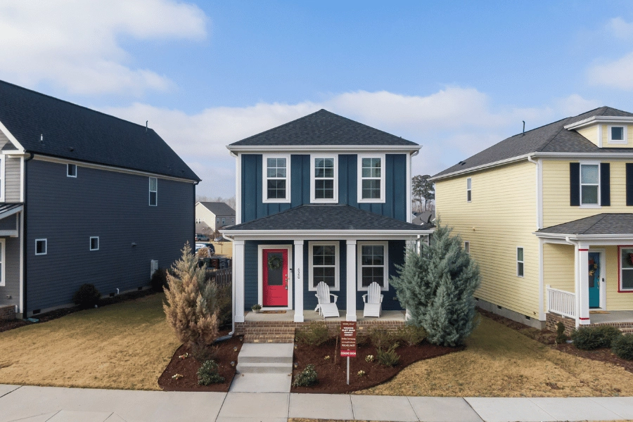 cute blue new-construction home in a neighborhood with a red front door